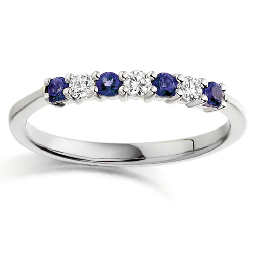 A seven stone ring with alternating blue sapphire and clear diamond stones set in a gold band.