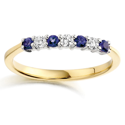 A seven stone ring with alternating blue sapphire and clear diamond stones set in a gold band.