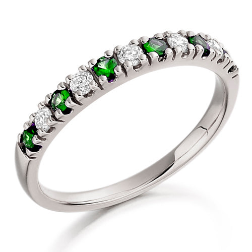 A half eternity ring with alternating emerald and diamond stones set along the band.