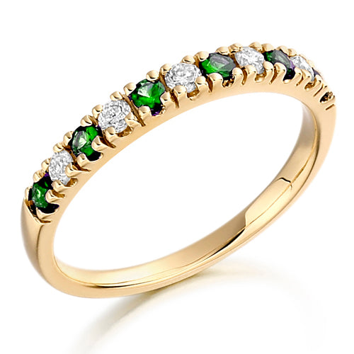A half eternity ring with alternating emerald and diamond stones set along the band.