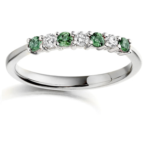 A seven stone ring featuring alternating emeralds and diamonds, set in a white gold band.