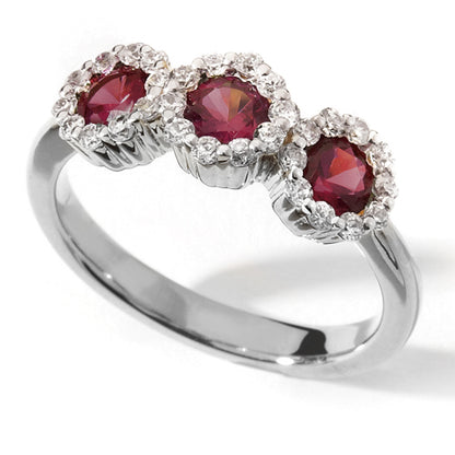 A Ruby Trilogy Ring with three red rubies set in a white gold band with halo diamonds around each ruby.